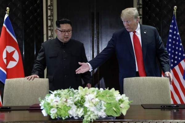 도널드 트럼프 미 대통령(오른쪽)이 12일 싱가포르 센토사섬의 카펠라 호텔에서 열린 김정은 북한 국무위원장과의 사상 첫 북미 정상회담 후 합의문에 서명하기에 앞서 김 위원장에게 자리에 앉으라고 권하고 있다.(사진=뉴시스)