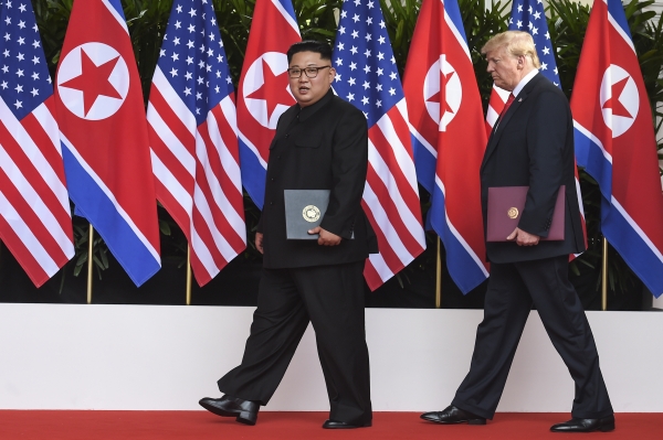 김정은 북한 국무위원장(왼쪽)과 도널드 트럼프 미 대통령이 6월 12일 싱가포르 센토사섬의 카펠라 호텔에서 첫 북미 정상회담 후 합의문에 조인한 뒤 각자 서명한 합의문을 들고 퇴장하고 있다.(사진=뉴시스)