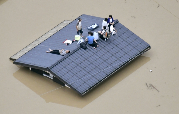7일 일본 오카야마(岡山)현 구라시키(倉敷)시에서 지붕에 대피한 주민들이 구조를 기다리고 있다. 이번 폭우로 심각한 피해를 입은 규슈지역과 중부지방은 7월 5일부터 72시간 동안 평년 7월 한 달 동안의 강수량보다 3배 이상 많은 폭우가 집중적으로 쏟아졌다. (사진=뉴시스)