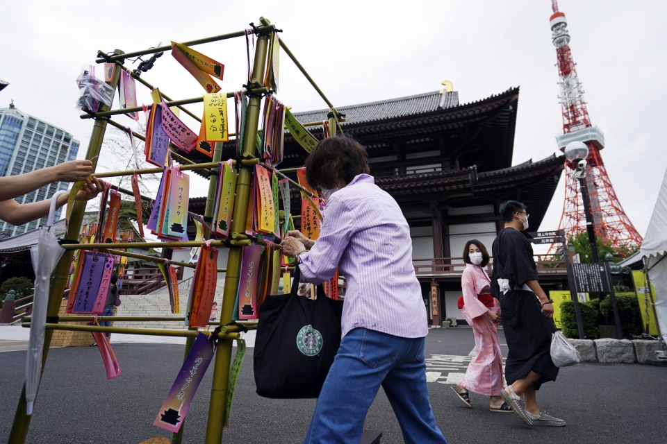 지난 7일 일본 도쿄 소재 한 절에서 칠월칠석(타나바나)을 맞아 시민들이 소원을 종이에 적어 대나무 장식에 묶고 있다.(사진=뉴시스)