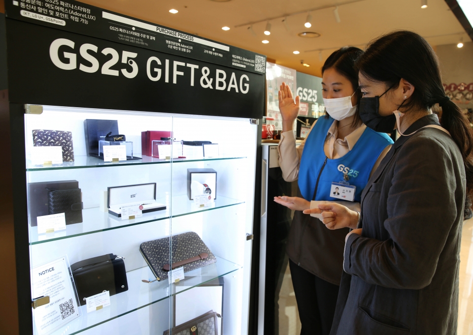 고객이 GS25 파르나스타워점에서 직원과 함께 명품 판매대를 살펴보고 있다. (사진=GS25)