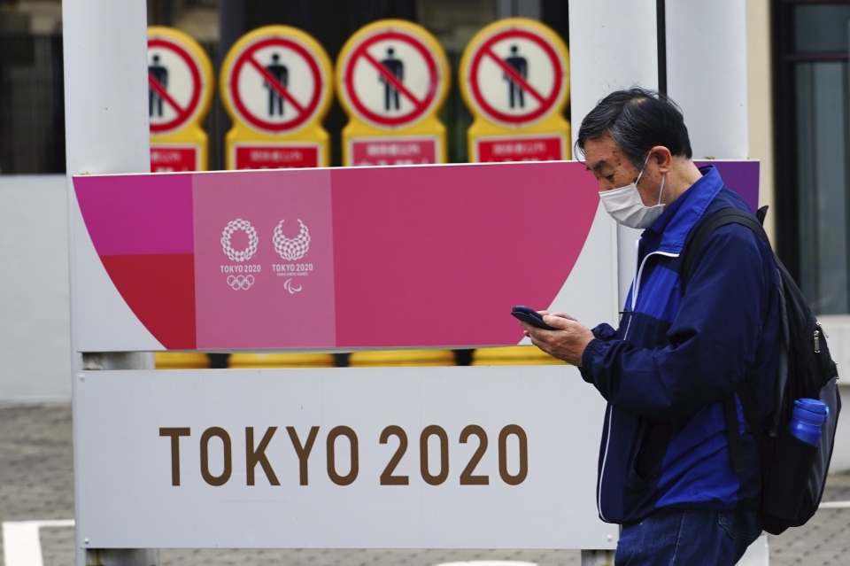 일본 도쿄에서 코로나19 확산 방지를 위해 마스크를 쓴 한 남성이 2020 도쿄올림픽·장애인올림픽 홍보물 앞을 지나가고 있다.  (사진=뉴시스/AP)