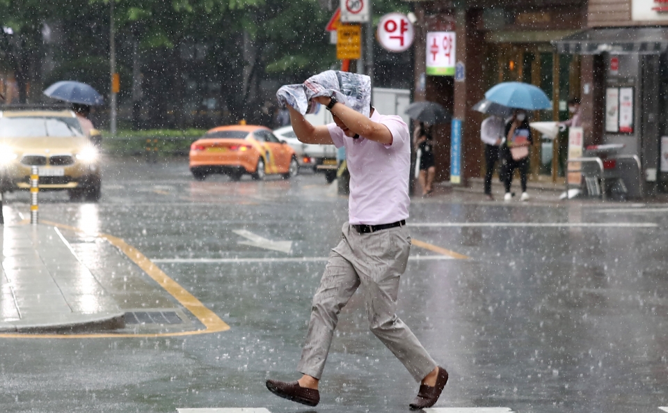 대기불안정에 의해 소나기가 내린 30일 오후 서울 종로구 세종문화회관 일대에서 한 시민이 신문을 머리에 쓰고 비를 피해 발걸음을 옮기고 있다. (사진=뉴시스)