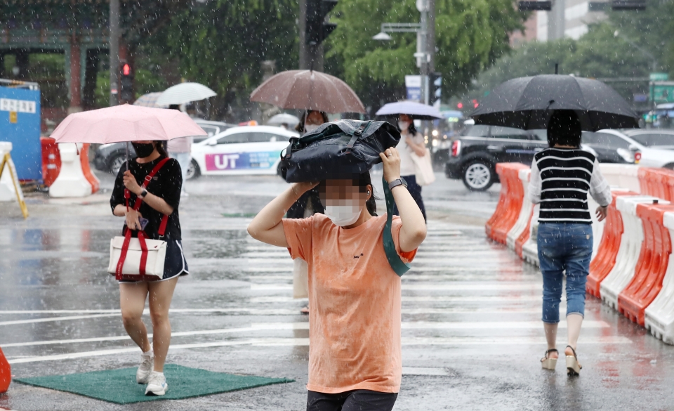 [서울=뉴시스]이영환 기자 = 대기불안정에 의해 소나기가 내린 30일 오후 서울 종로구 광화문네거리 일대에서 한 시민이 가방을 머리에 쓰고 비를 피해 발걸음을 옮기고 있다. 2021.06.30. 20hwan@newsis.com