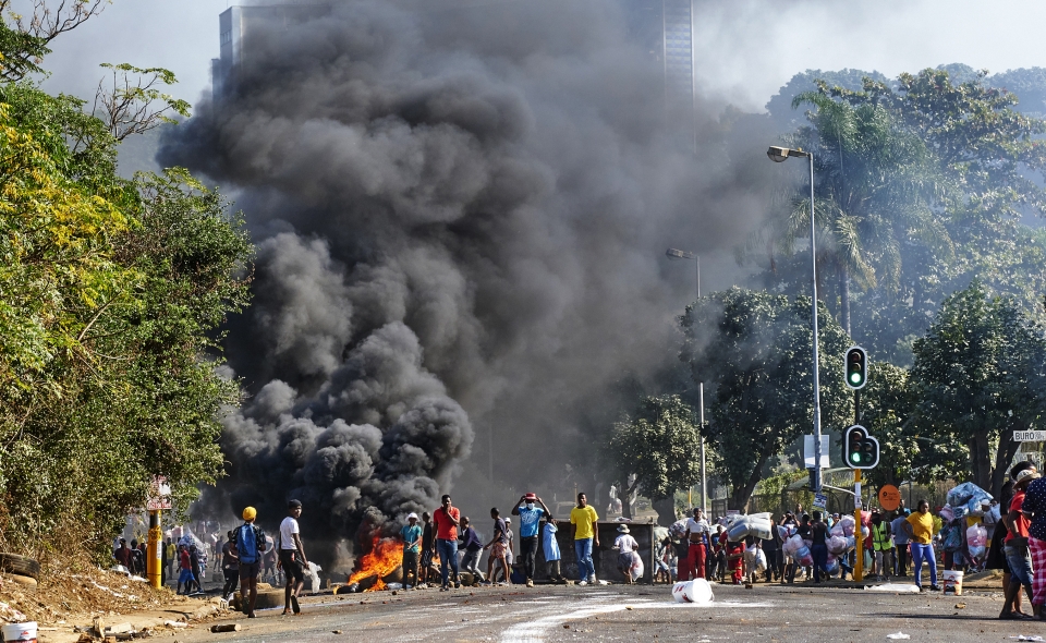 지난 12일 남아프리카공화국 더반 거리가 불타는 와중에 주민들이 한 쇼핑센터를 약탈하고 있다. (사진=AP·뉴시스)