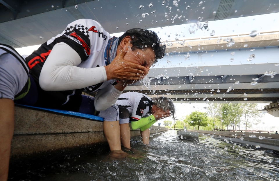 20일 오전 서울 영등포구 여의도한강공원에서 자전거를 타던 시민들이 물에 발을 담그고 세수를 하며 무더위를 식히고 있다. (사진=뉴시스)