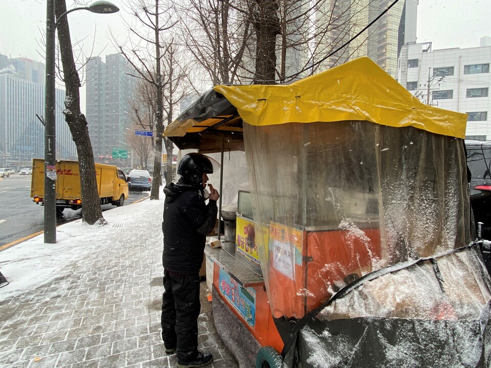 19일 공덕역 인근에서 눈을 피해 붕어빵 가게에서 붕어빵을 먹고 있는 오토바이 기사. (사진=박은정 기자)