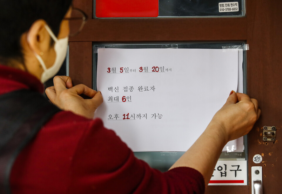 서울시내 한 식당에서 관계자가 새로운 거리두기 안내문을 붙이고 있다. (사진=뉴시스)