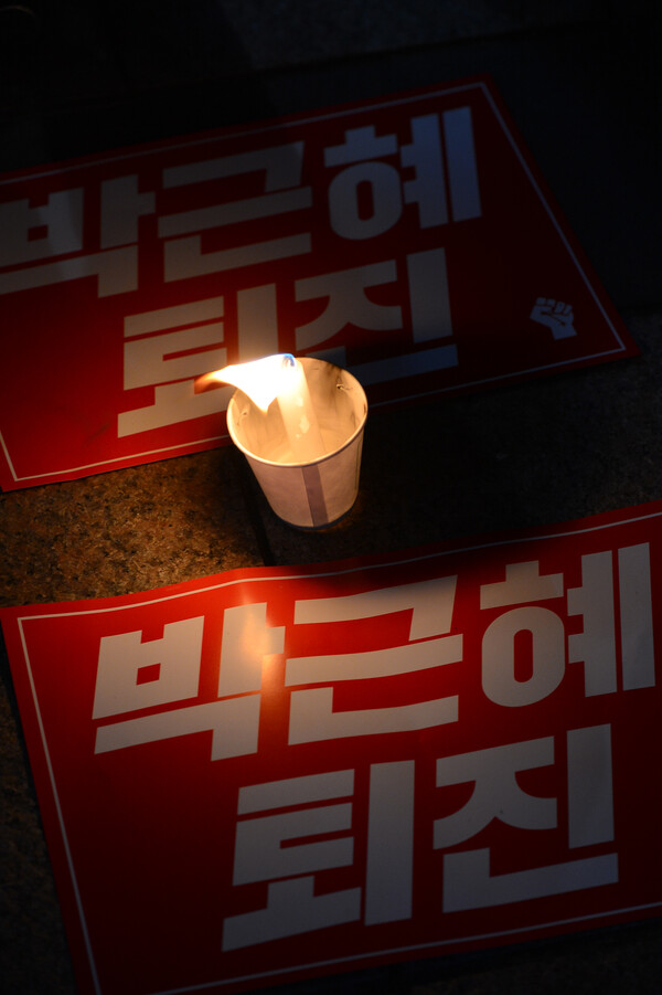 2016년 서울 광화문에서 열린 박근혜 전 대통령 탄핵 시위에 한 참석자가 촛불을 앞에 두고 있다. [사진=뉴시안]
