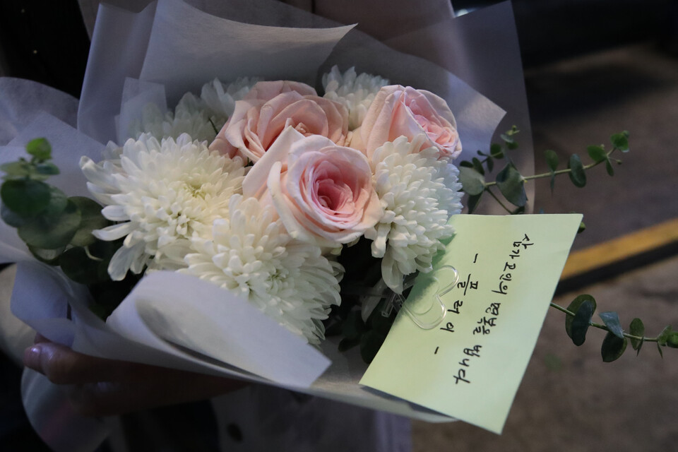 지난 30일 오후 서울 용산구 이태원 압사 사고 인근에 마련된 추모공간에서 한 시민이 헌화할 꽃을 들고 추모하기 위해 대기하고 있다. [사진=뉴시스]