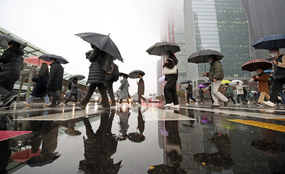 겨울비가 내리는 지난 13일 오전 서울 영등포구 여의도 환승센터에서 시민들이 우산을 쓰고 이동하고 있다. [사진=뉴시스]