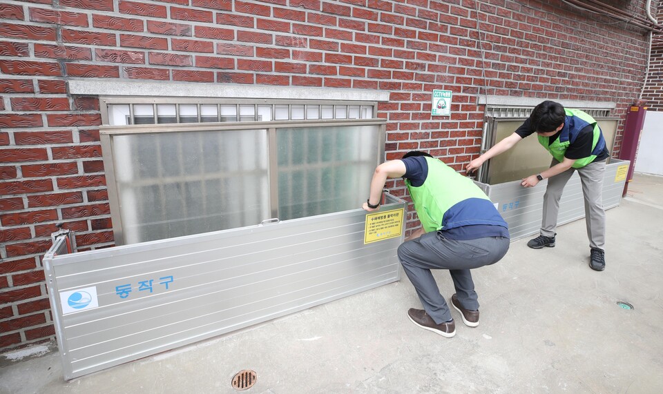 지난 6월 23일 오전 서울 동작구청 직원들이 동작구 도림천 저지대 주택가 반지하 세대에 수해 예방용 물막이판을 설치하고 있다. [사진=뉴시스]