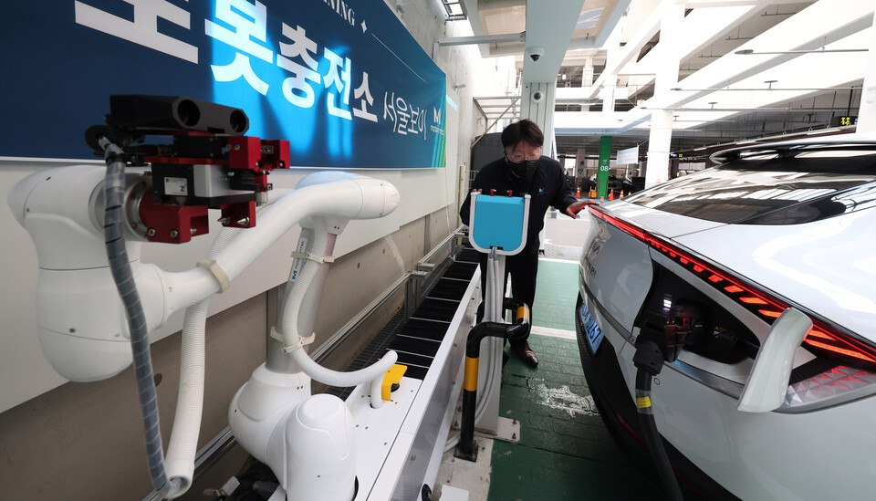 서울 강서구 신방화역 공영주차장에서 전기차 충전기 전문기업 모던텍 관계자가 AI 기반 로봇 자율 충전 시스템 '서울 보이' 시연을 하고 있다. '서울 보이'는 로봇팔 형태로 로봇 1대가 전기차 3대를 동시에 충전시킬 수 있는 자동화 시스템이다. [사진=뉴시스]